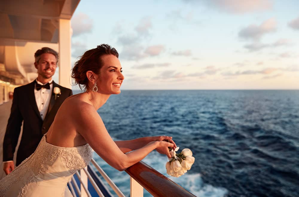 Bride at railing with ocean sunset
